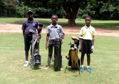 Three golfers with their golf bags in a golf course.