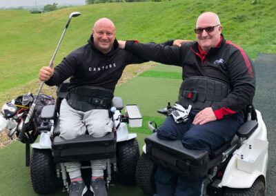 TWO MEN IN PARAGOLFER VEHICLES with their arms joined