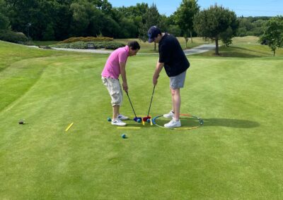 Dad and son on putting green, putting balls towards a multi-coloured target