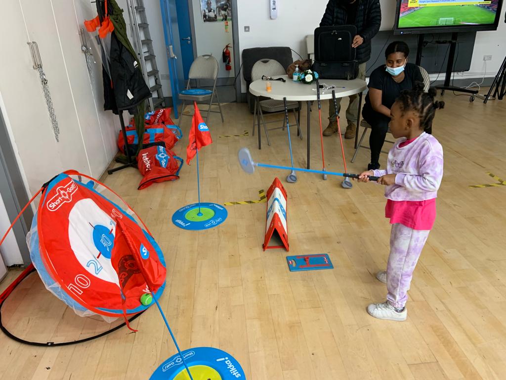 Young girl hitting a ball onto a round target.