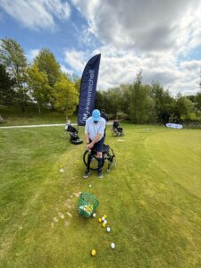 Man with prosthetic right leg hitting golf shots on a chipping green
